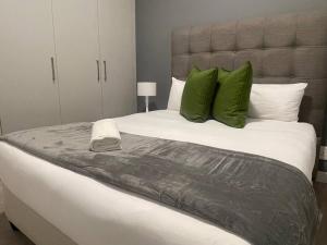 a bedroom with a large bed with green pillows at Lovely and Cosy 2 bedrooms Space in Rosebank in Johannesburg