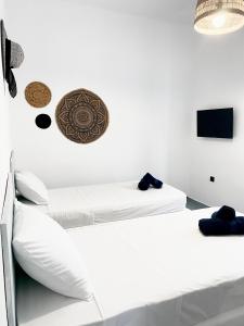 a white bedroom with two beds and a tv at The Greek side of life! in Artemida