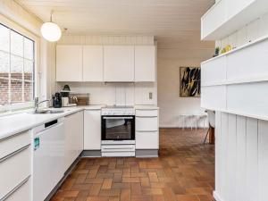 uma cozinha com armários brancos e piso em madeira em 8 person holiday home in Bl vand em Blåvand