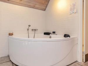 uma banheira branca sentada num quarto em 8 person holiday home in Bl vand em Blåvand