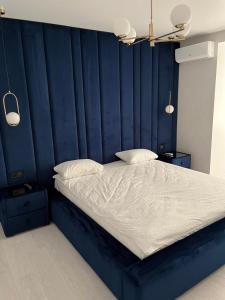 a bed with a blue headboard with two pillows at Апартаменти Люкс3 зі світлом in Khmelnytskyi