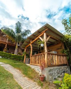 a wooden house with a porch and a palm tree at Finca Valentina in Valladolid