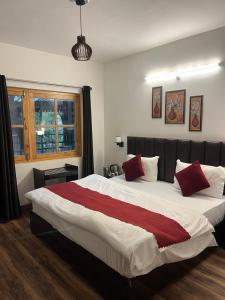 a bedroom with a large bed with red pillows at Cedar Woods Resort in Nainital