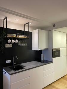 a kitchen with white cabinets and a black wall at Appartment bezaubernder Landblick in Timmendorfer Strand