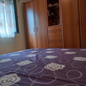 a bed with a purple blanket with white flowers on it at Ksenija apartman uz more in Krasici