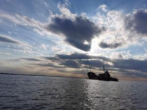 un barco en el agua bajo un cielo nublado en Pensiunea sellina, en Sulina
