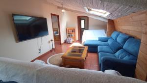 a living room with a blue couch and a tv at Casa Millar. in Huergas y El Millar