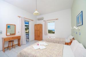 a bedroom with two beds and a desk and a mirror at Psili Ammos Studios in Aliko Beach
