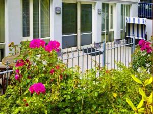 a house with pink flowers in front of a fence at Ferienwohnung Warnemünde in Warnemünde
