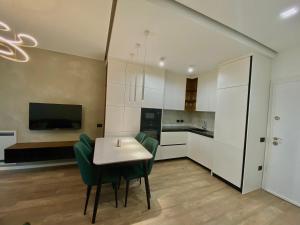 a kitchen with white cabinets and a table and chairs at Lux Apartment 02 + Free Parking Post in Tirana