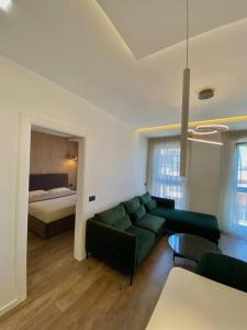 ein Wohnzimmer mit einem grünen Sofa und einem Bett in der Unterkunft Lux Apartment 02 + Free Parking Post in Tirana