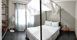 1 dormitorio con cama con dosel y ventana en Kalahari Sand Ridge Inn en Livingstone