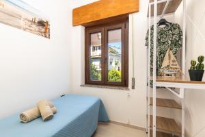 Habitación pequeña con cama azul y ventana en Appartamento Ogliastra, en Santa Maria Navarrese