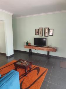 sala de estar con TV y mesa en Kalahari Sand Ridge Inn, en Livingstone