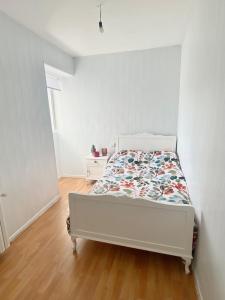 Dormitorio blanco con cama con colcha de flores en A casa do pai, en Pontevedra