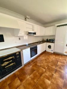 uma cozinha com armários brancos e piso em azulejo em A casa do pai em Pontevedra
