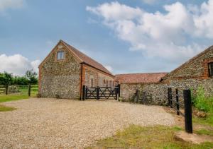 an old stone barn with a gate in front of it at The Hayloft in Tatterford