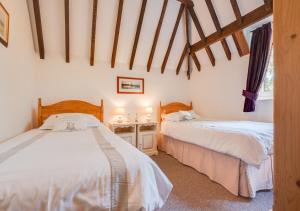 a bedroom with two beds and a desk in it at The Maltings in Ludham