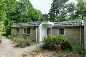 una pequeña casa de ladrillo con garaje blanco en Vakantiehuis Lochem, en Lochem