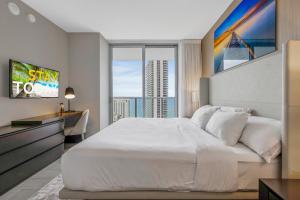 ein Schlafzimmer mit einem großen weißen Bett und einem großen Fenster in der Unterkunft HYDE HOUSE - Luxury Waterfront 2BR 2BA Apartment Suite with direct ocean view, roof top pool, resort amenities in Hollywood