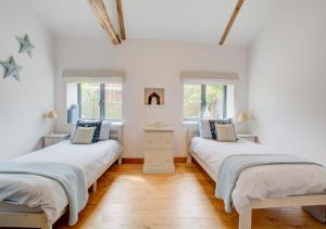 twee bedden in een kamer met witte muren en houten vloeren bij The Old Cart Lodge 