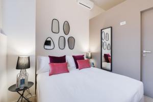 een witte slaapkamer met een groot wit bed met rode kussens bij Sweet Inn - Porta Romana in Milaan