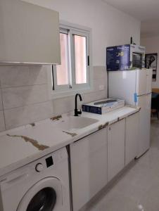 uma cozinha com um lavatório e uma máquina de lavar roupa em פטל em Bersebá