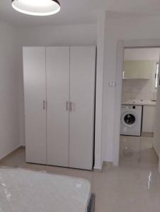 uma cozinha branca com armários brancos e um micro-ondas em פטל em Bersebá