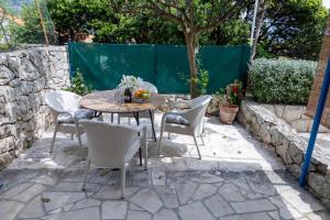 - une table et des chaises sur une terrasse avec un arbre dans l'établissement Art & Gallery Vacation Home, à Korčula