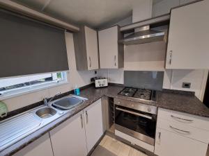 a small kitchen with white cabinets and a sink at Withernsea luxury caravan hire in Waxholme