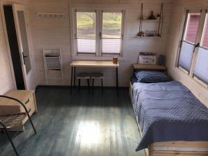 Zimmer mit einem Bett, einem Schreibtisch und einem Tisch in der Unterkunft WOMOCAMP Holzhütte 1 in Saulkrasti