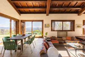 a living room with a table and green chairs at Oasi di Mastarone - Il vino e le Rose in Momperone
