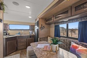a kitchen and dining area of an rv with a table at JT Village Campground - Lil Miss Daisy in Joshua Tree