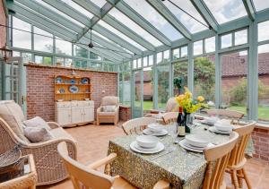 a conservatory dining room with a table and chairs at Watts Cottage in Upton