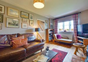 The Stables في Thurgarton: غرفة معيشة مع أريكة جلدية وتلفزيون