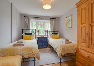 The Stables في Thurgarton: غرفة نوم بسريرين مع وسائد صفراء