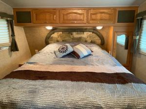 a bed with two pillows on it in an rv at Comfortable RV in a farm in Nanoose Bay