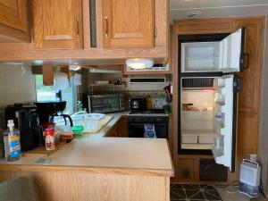 a kitchen with an open refrigerator and a stove at Comfortable RV in a farm in Nanoose Bay