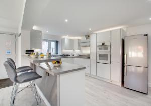 a white kitchen with a counter and a chair in it at The Retreat in Holt