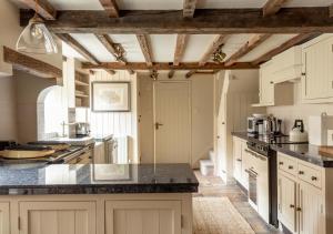 a large kitchen with white cabinets and black counter tops at Willow Cottage in Wighton