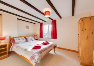 a bedroom with a bed with red towels on it at Tones Cottage in Great Ryburgh