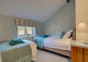 dwa łóżka w sypialni z ptakami na ścianie w obiekcie Wren Cottage w mieście Aylsham