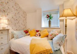 a bedroom with a bed with pillows and a window at Thimble Cottage in Dersingham
