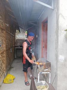 a man is cooking food on a grill at ANNI'S BEACH HOUSE in Lucena