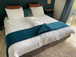 Una cama grande con una manta azul. en la chambre d hotes de marie indépendante et sa terrasse avec vue panoramique proche alpes mancelles, en Sillé-le-Guillaume
