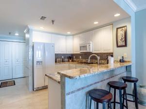 Una cocina con gabinetes blancos y taburetes de bar. en Emerald Isle #1007, en Pensacola Beach