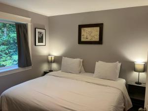 a bedroom with a large white bed with two lamps at Sienna's Tree House (Tall Trees And Salty Breeze) in Tofino