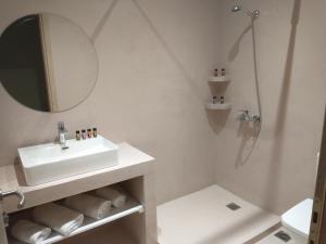 La salle de bains blanche est pourvue d'un lavabo et d'une douche. dans l'établissement Menta, à Litochoro