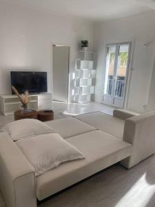 ein weißes Wohnzimmer mit einem Sofa und einem TV in der Unterkunft Beautiful central beach apartment in Juan Les Pins in Antibes