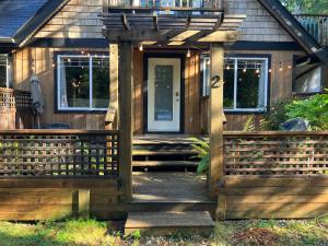 uma casa de madeira com um portão e um alpendre em Sienna's Tree House (Tall Trees And Salty Breeze) em Tofino